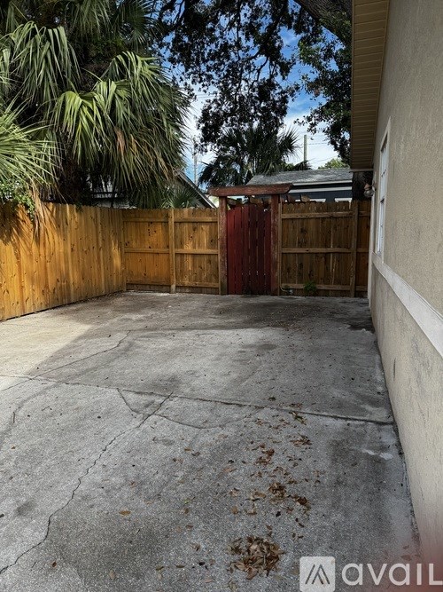 A backyard with a wooden fence and a red gate.