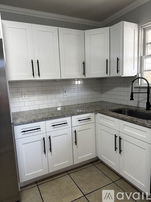 A kitchen with white cabinets and a granite countertop.
