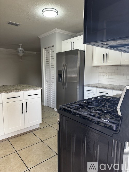 A kitchen with a black stove top and white cabinets.