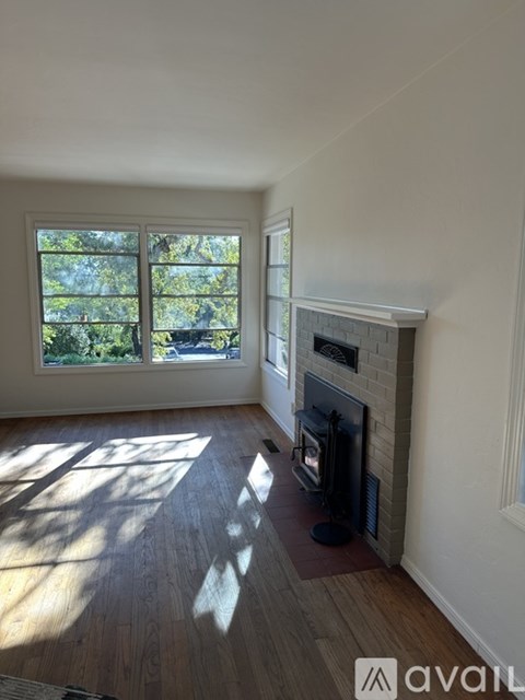 A room with a fireplace and a window overlooking trees.