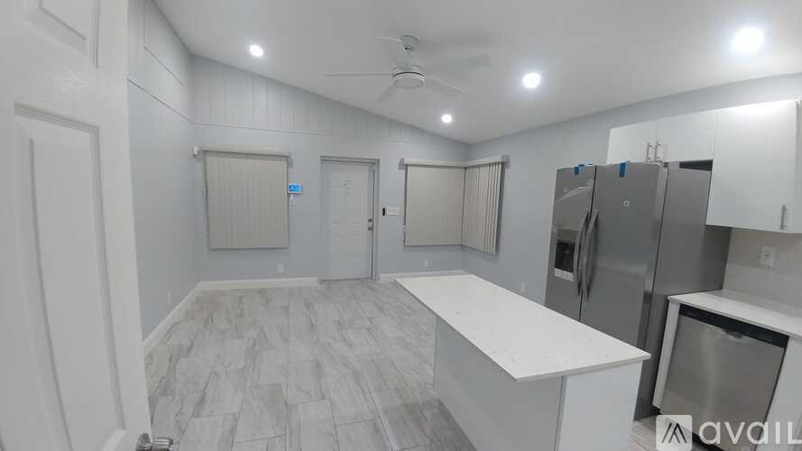 A spacious kitchen with white cabinets and a marble countertop.