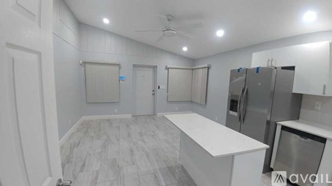 A spacious kitchen with white cabinets and a marble countertop.