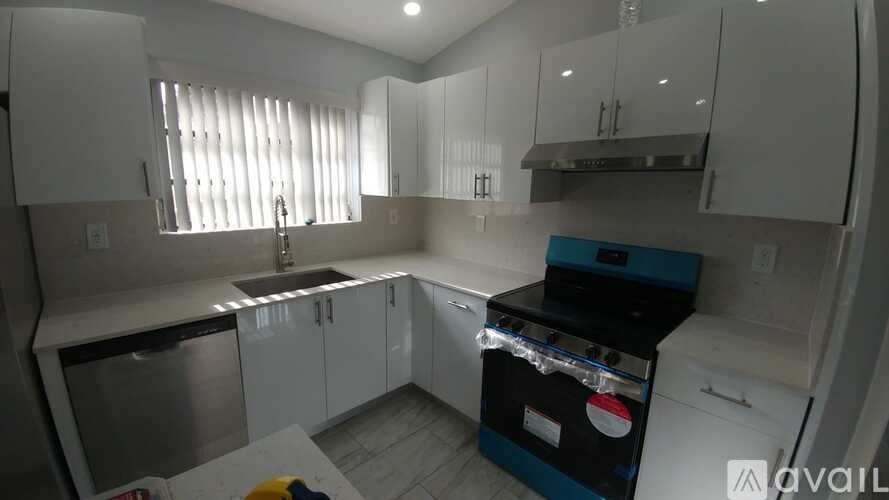 A kitchen with white cabinets and a blue stove top oven.