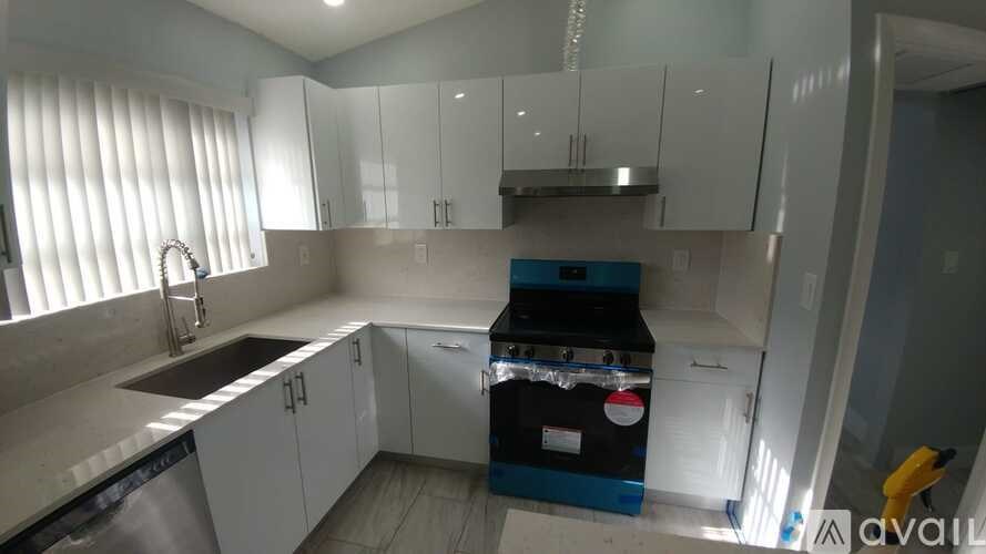 A kitchen with white cabinets and a blue appliance.
