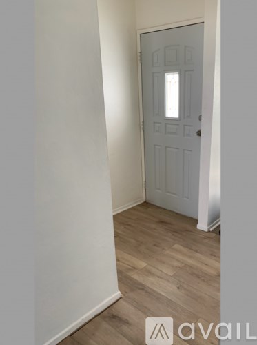 A white door is in a room with wooden floors.
