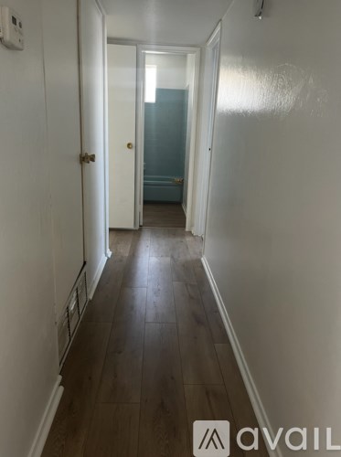 A hallway with a wooden floor and white walls.