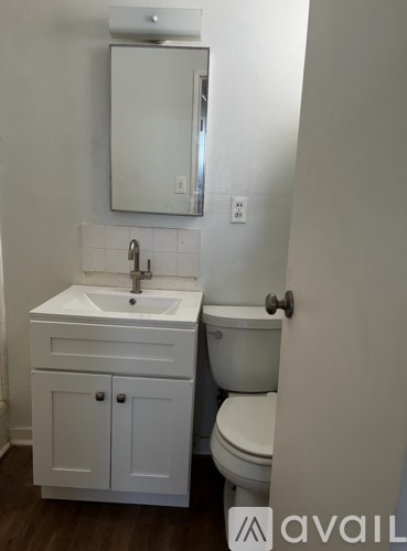 A white bathroom with a toilet, sink and medicine cabinet.