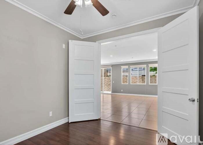A room with a ceiling fan and a door leading to another room.