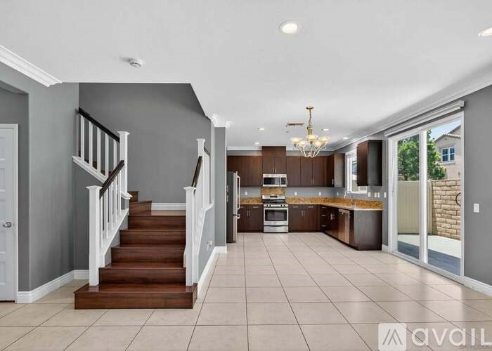 A spacious kitchen and living room with a staircase leading to the upper floor.