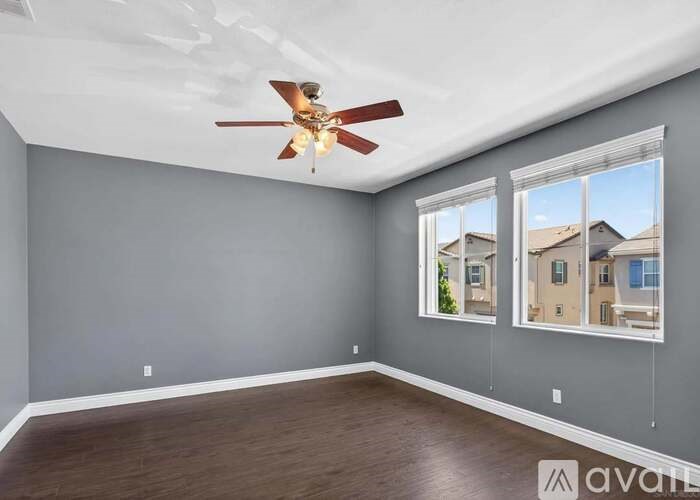 A room with a ceiling fan and two windows.