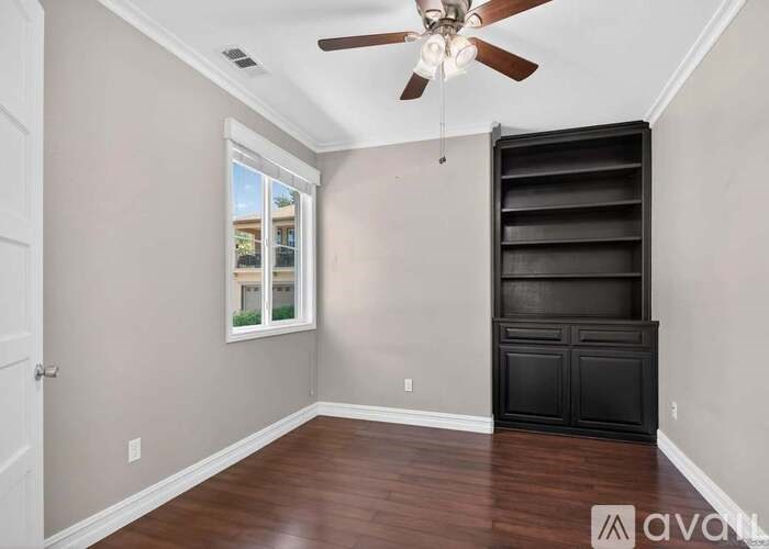 A room with a ceiling fan and a large black cabinet.