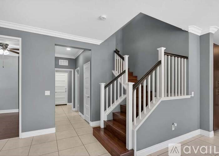 A hallway with a staircase and a fan.