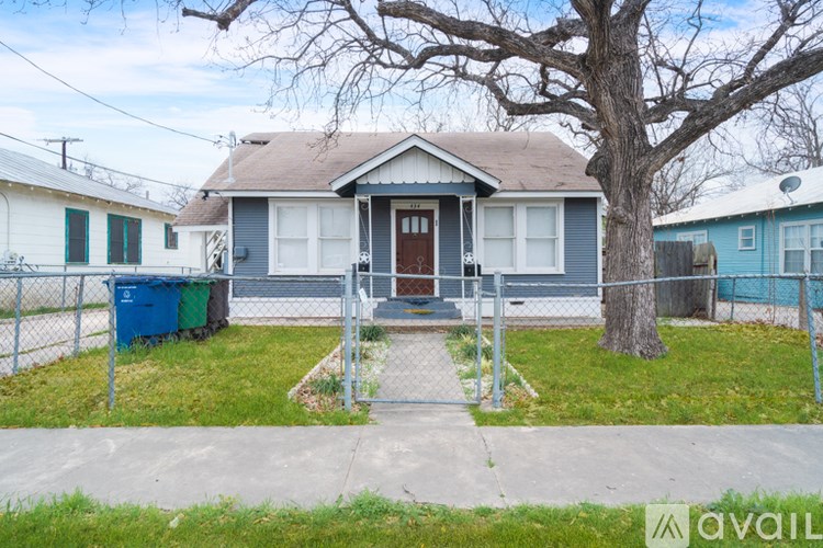 A house with a blue door and a brown roof is surrounded by a fence.