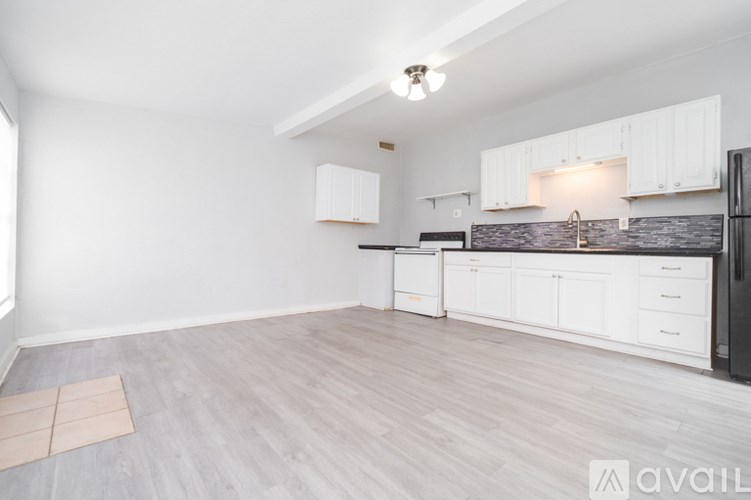 A kitchen with white cabinets and a black refrigerator.