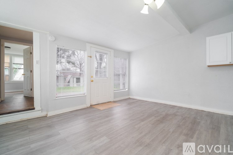 A spacious room with wooden flooring and white walls.