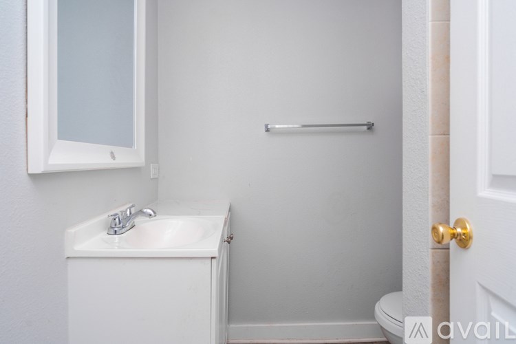 A white bathroom with a sink, mirror, and toilet.