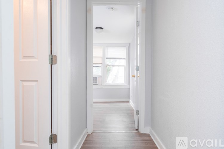 A hallway with a door on the left and a window on the right.