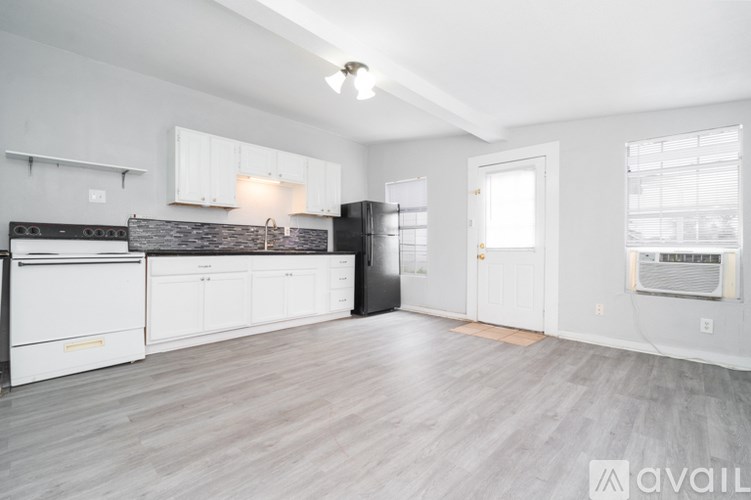 A spacious kitchen with white cabinets and a black refrigerator.