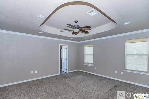 A spacious room with a ceiling fan and a door leading to another room.