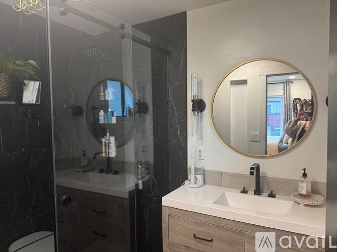 A bathroom with a marble wall and a round mirror above a sink.