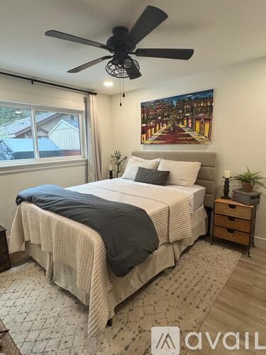 A bedroom with a large bed and a ceiling fan.