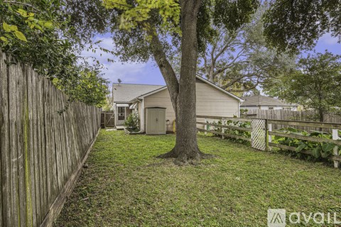 A tree in a yard with a house in the background.