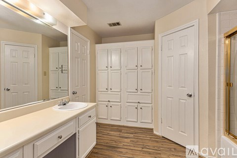 A bathroom with a sink, mirror, and cabinets.