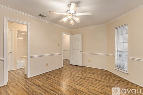 A spacious room with wood flooring and a ceiling fan.