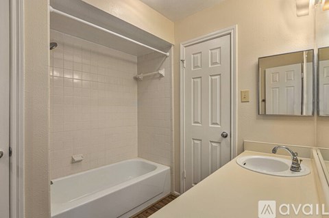 A bathroom with a white tub, sink, and door.