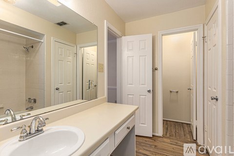 A bathroom with a sink, mirror, and two doors.