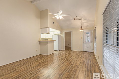 A spacious room with wooden flooring and a ceiling fan.