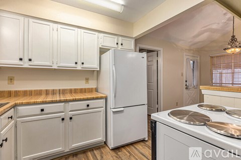 A kitchen with white cabinets and a white refrigerator.