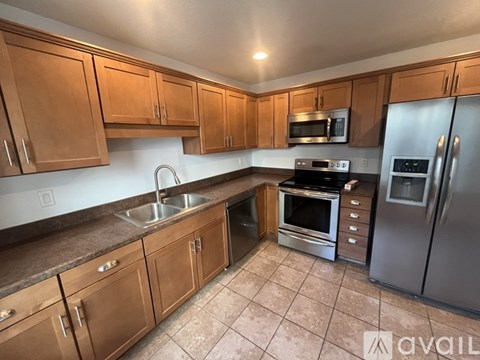 A kitchen with wooden cabinets and a stainless steel refrigerator.