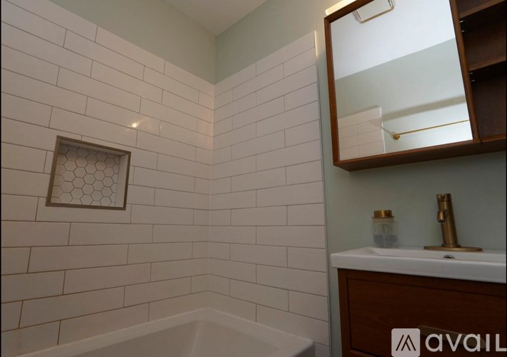 A bathroom with a white tiled wall and a wooden medicine cabinet.