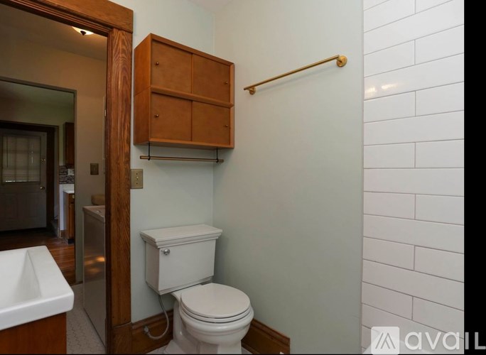 A white toilet sits under a cabinet in a bathroom.