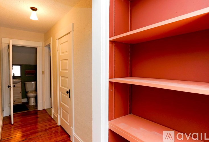 A hallway with a toilet and sink visible through the door.