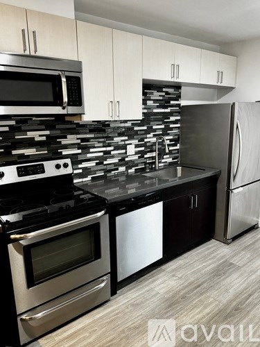 A kitchen with black and white appliances and a stone backsplash.