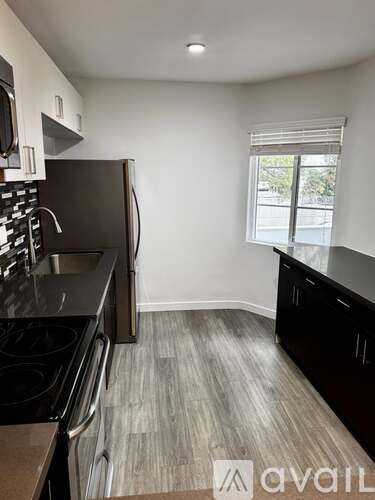 A kitchen with black appliances and wooden flooring.