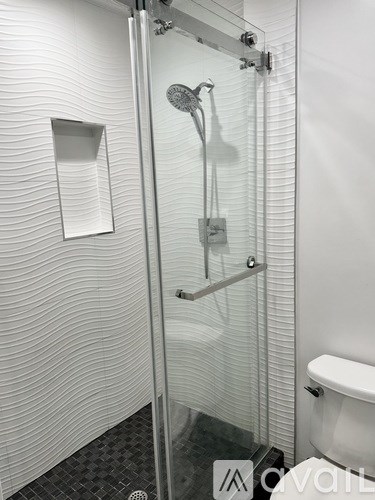 A modern bathroom with a glass shower door and a white toilet.