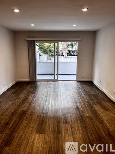 A room with wooden flooring and a large glass door.