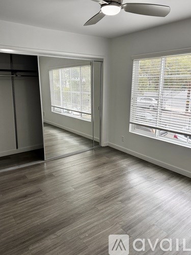 A room with a ceiling fan and a large window with blinds.