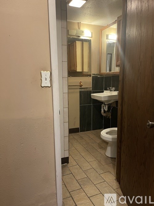 A bathroom with a toilet, sink, and mirror.