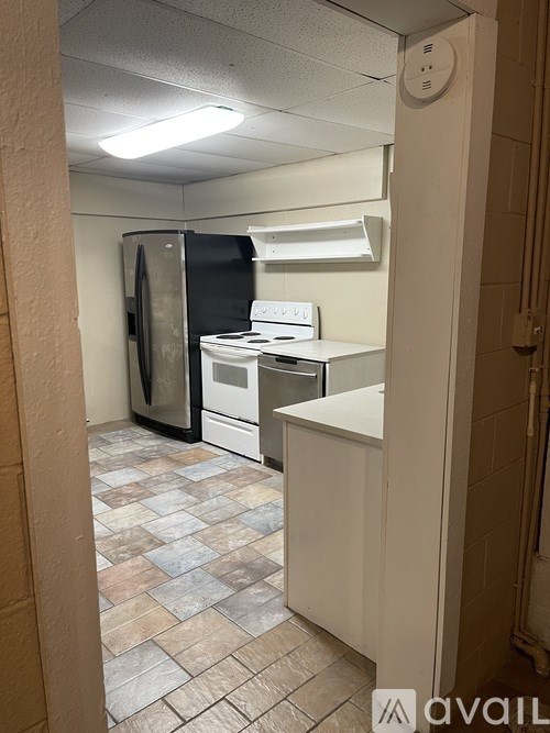 A kitchen with a black refrigerator, white oven, and a white counter.