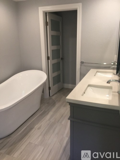 A white bathtub sits in a bathroom next to a sink.