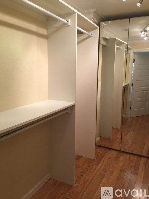 A white closet with a mirror on the wall.