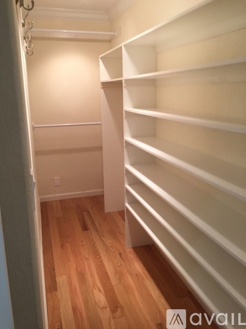 A long white shelving unit in a room with wooden floors.