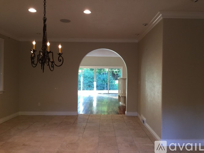A room with a chandelier and a large arched window.