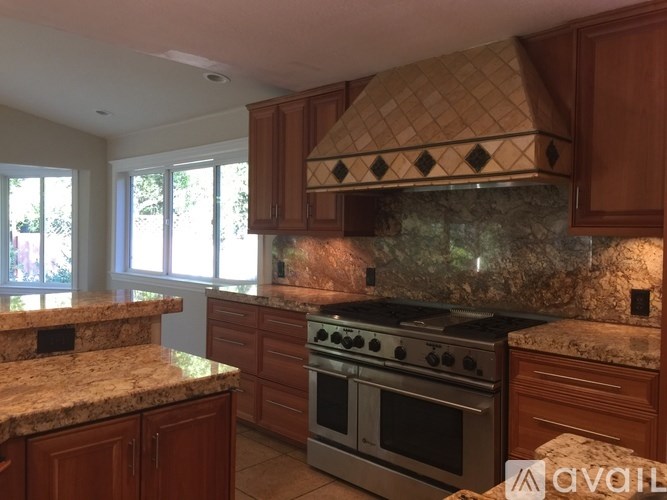 A kitchen with granite countertops and a tile hood.