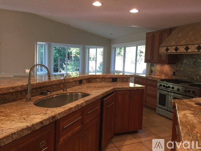 A kitchen with brown cabinets and a marble countertop.