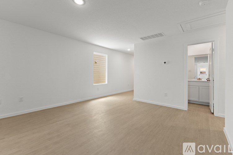 A large empty room with wooden flooring and white walls.